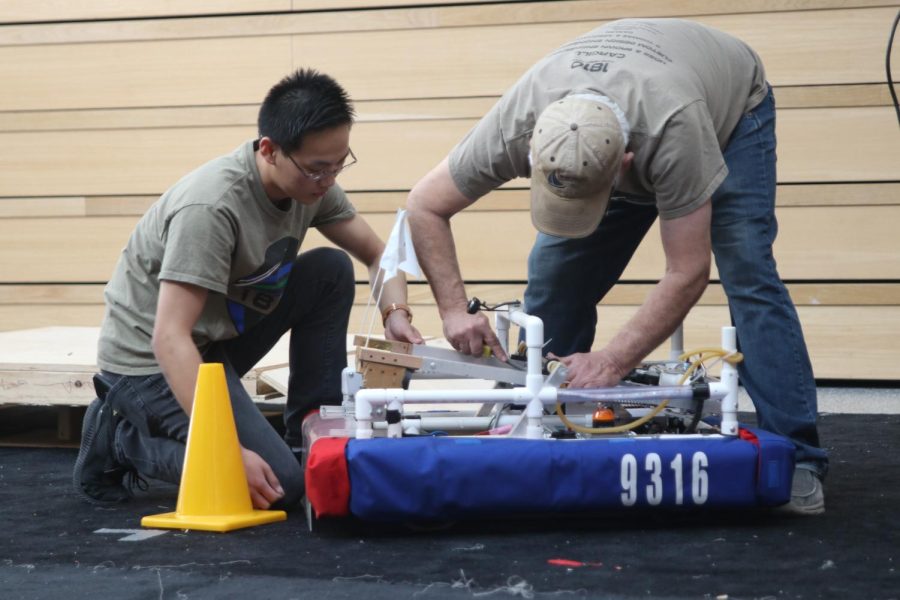 Following its exhibition, freshman Zach Chang holds the ramp in place on the JV team’s robot while mentor Gary Hannah measures its width Saturday, Feb. 25.