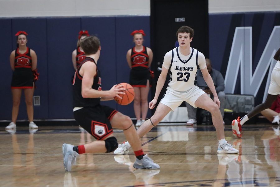 To block his opponent from reaching the basket, senior Ryan Cummings stands in front of the hoop.