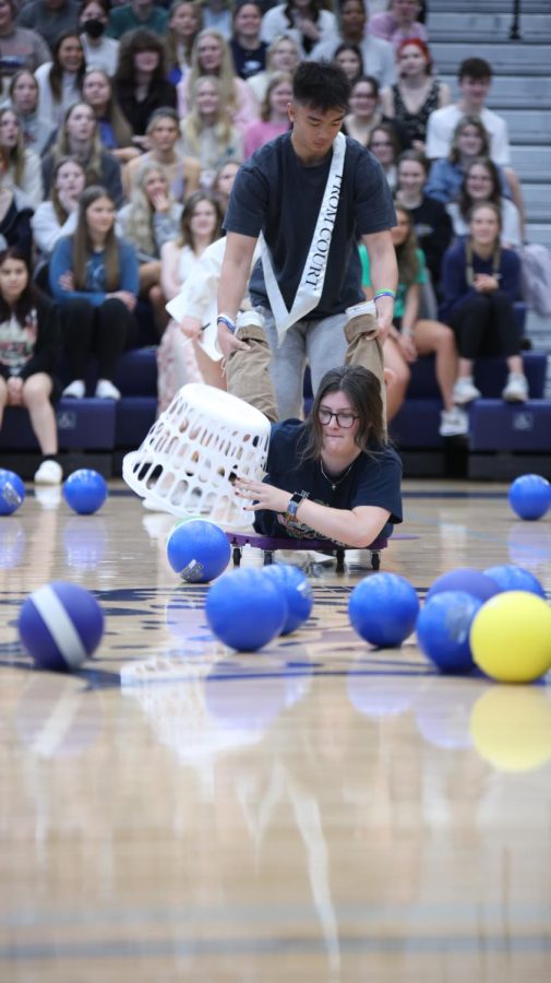 Being pulled by her partner, senior Reece Moulthrop tries to grab balls with her basket. 