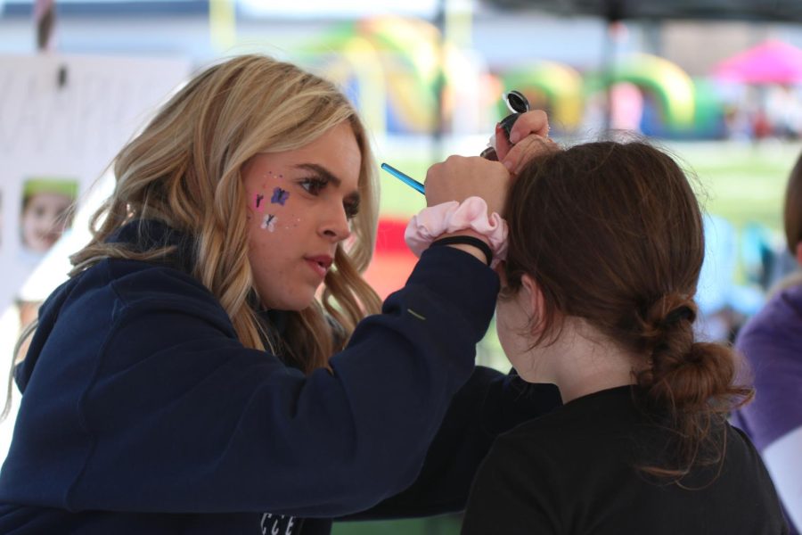Concentrating hard, sophomore Logan Miller paints on a girls face.