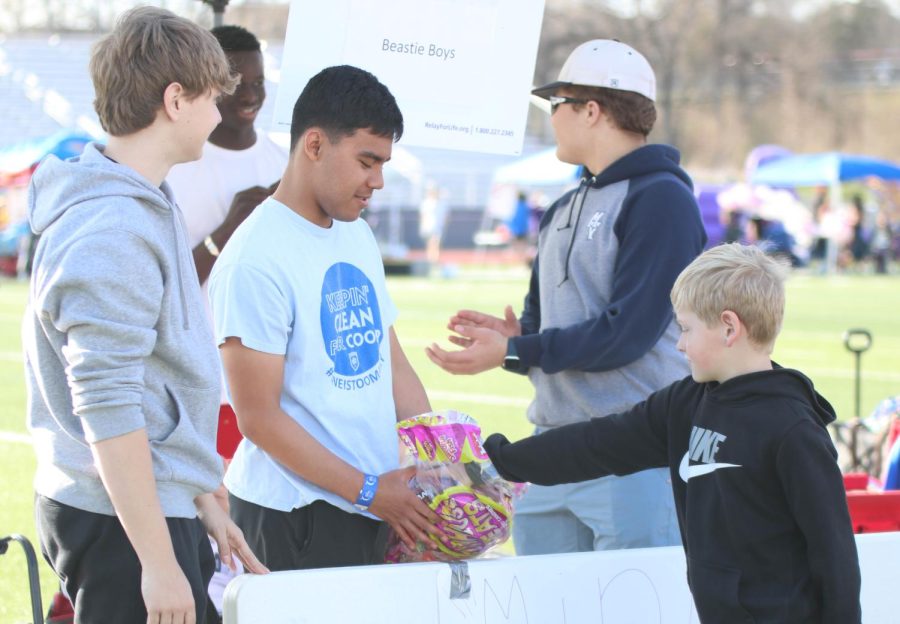 Junior Isaac Funes gives a kid candy after playing his mini golf game.