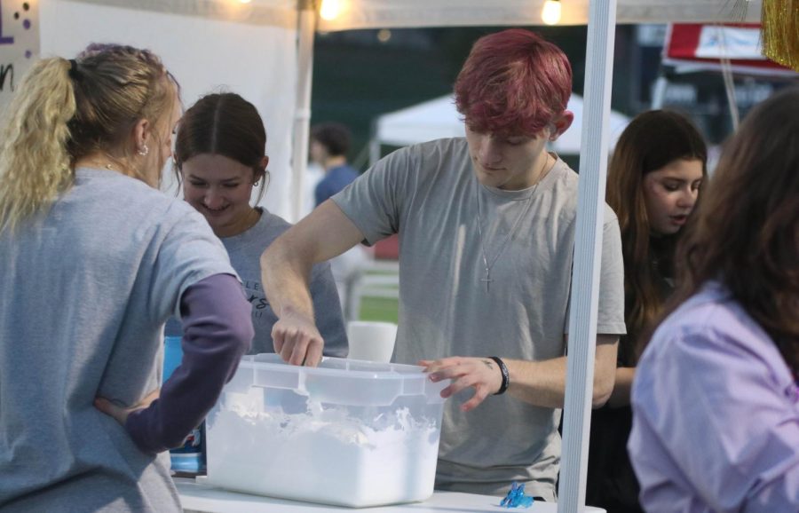 Junior Bryant Wiltse stirs together ingredients at a slime making booth.