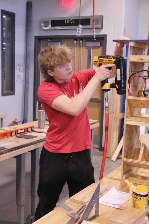 Building a battery cart for the junior varsity team, sophomore Jackson Pursell uses a nail gun to join pieces of plywood Saturday, Feb. 25.
