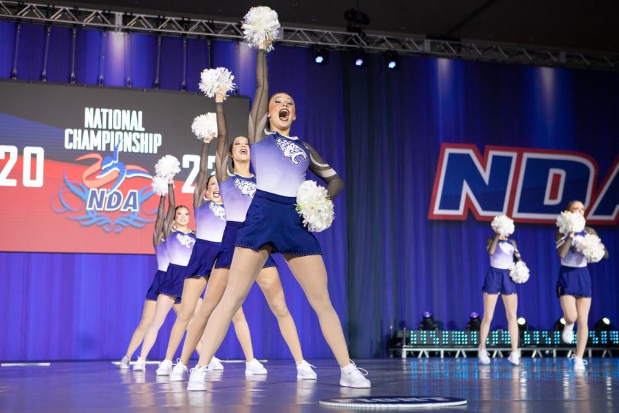 Poms waving in the air, junior Halle Wampler leads the team in their NDA medium varsity game day competition.