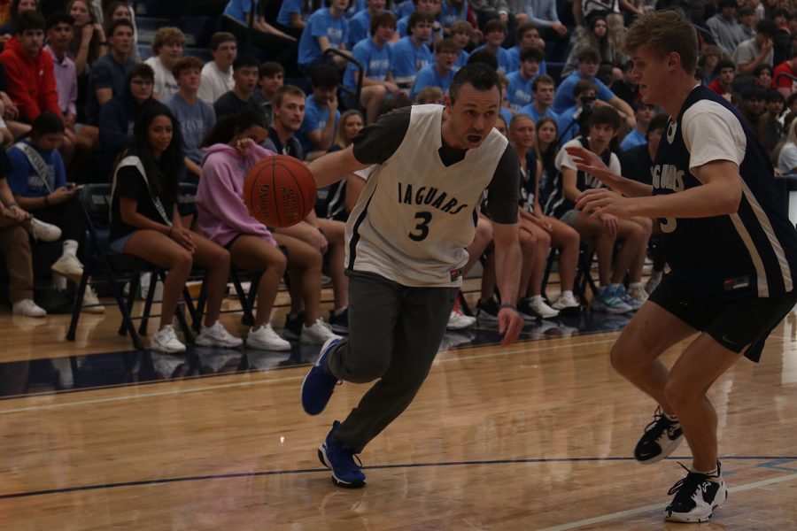 Dodging senior Tate Nekola, business teacher Adam Runyan scores another point for the teacher basketball team.