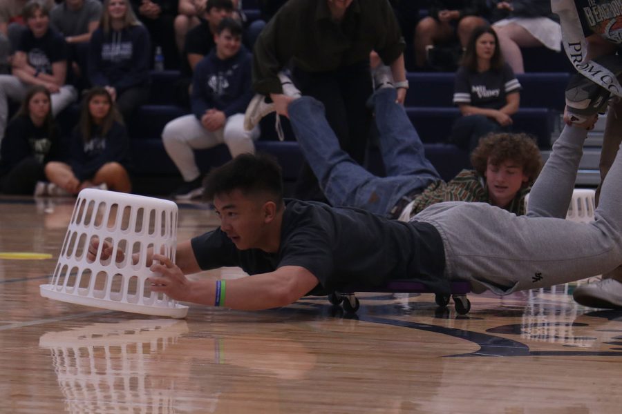 Being pushed on a scooter, senior Dylan Nguyen prepares to grab a ball.