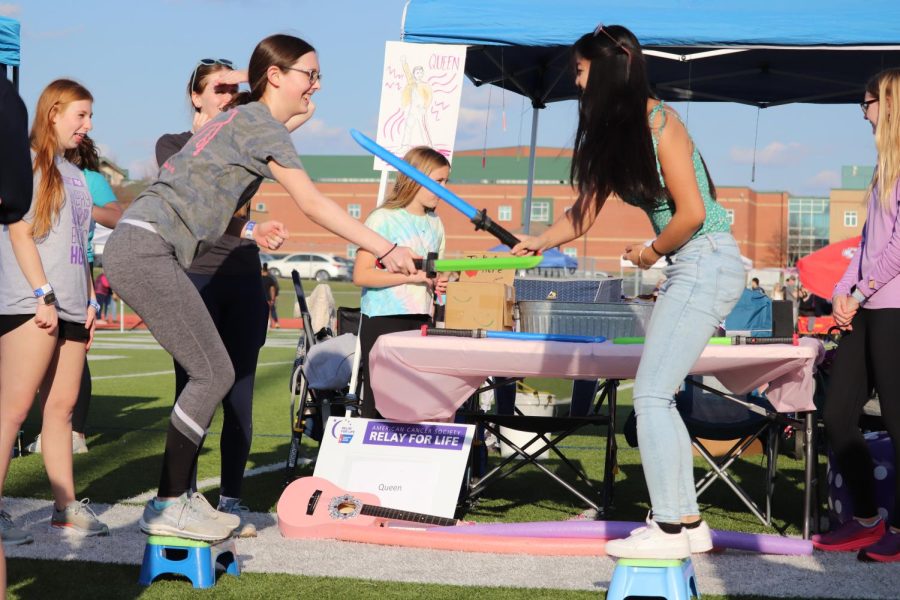 Atop small stools, sophomores Halle Nelson and Alivia Thatlor battle to knock the other off with plastic swords. 