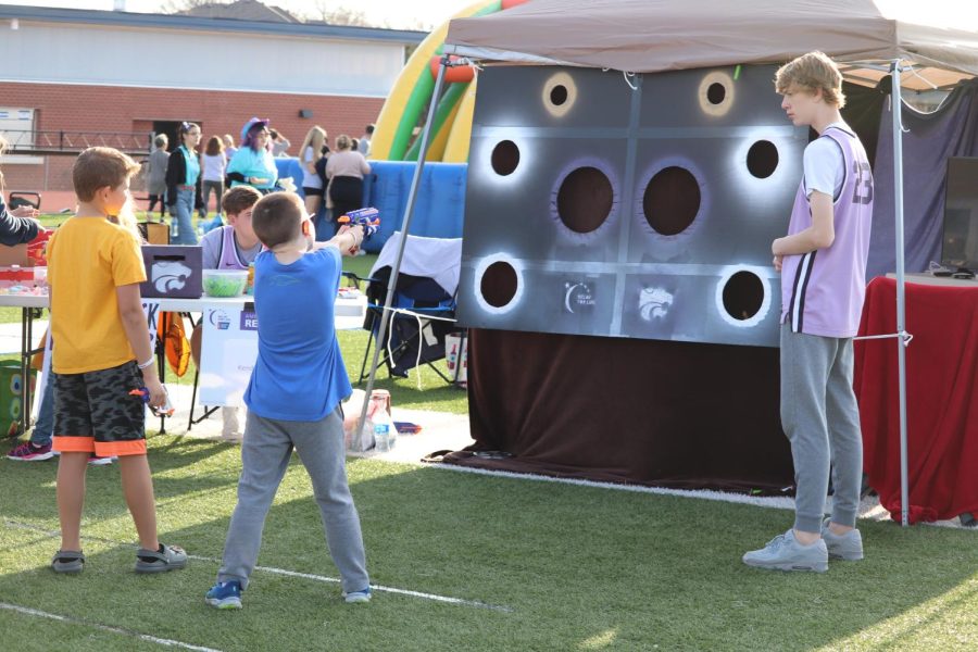 Hands up, a student holds a Nerf gun pointed at the targets. 