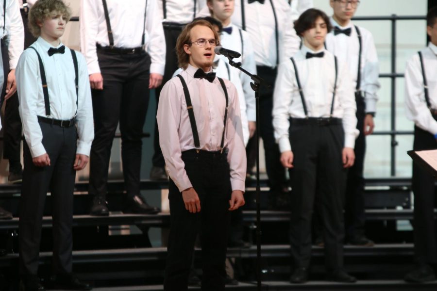 At the front of the stage, senior Alex Armstrong sings a solo. 