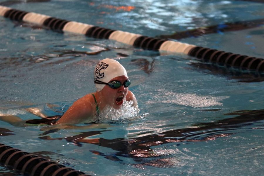 Coming up to breathe, sophomore Cora Jones swims to the end of the lane during the 100 meter breaststroke. 