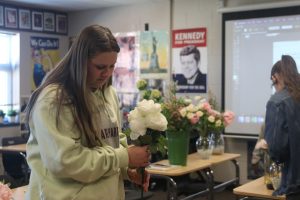 In preparation for this years prom, junior Avery Gullach-Ruiz carefully places a group of fake white roses into a vase.