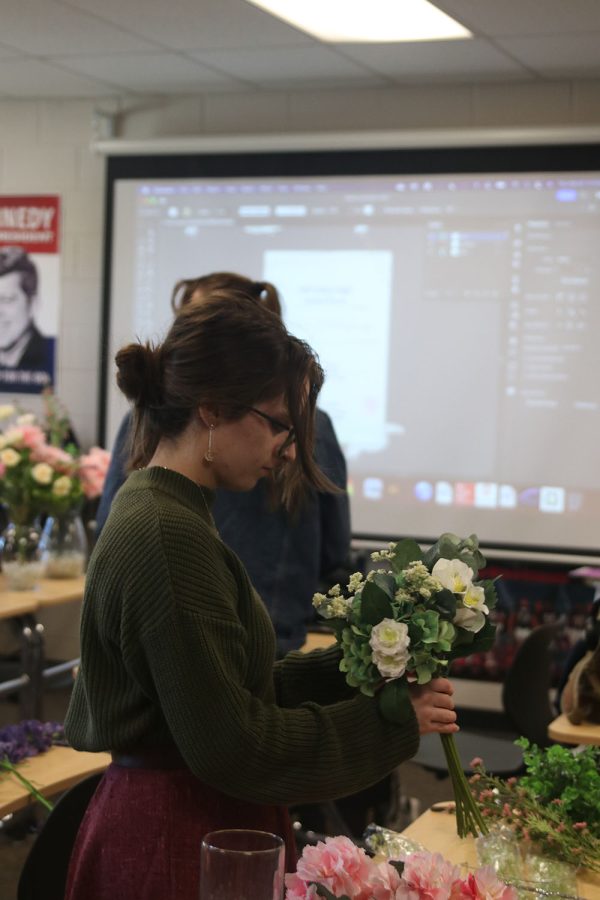 Junior Anna Zwahlen carefully unravels a bouquet of fake flowers to place into vases in preparation for prom. 
