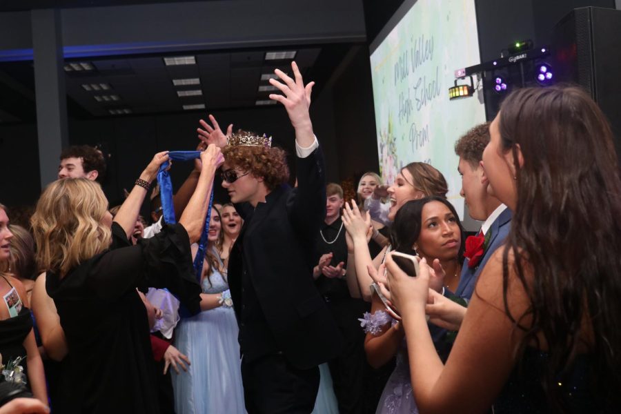 Accepting his prom king sash, senior Finn Campbell raises his hands in celebration.