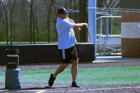 Concentrating on hitting the ball, JV head coach Chris Borchers swings the bat during a drill at practice. Coach Borchers has enjoyed sharing his love of baseball with the team.