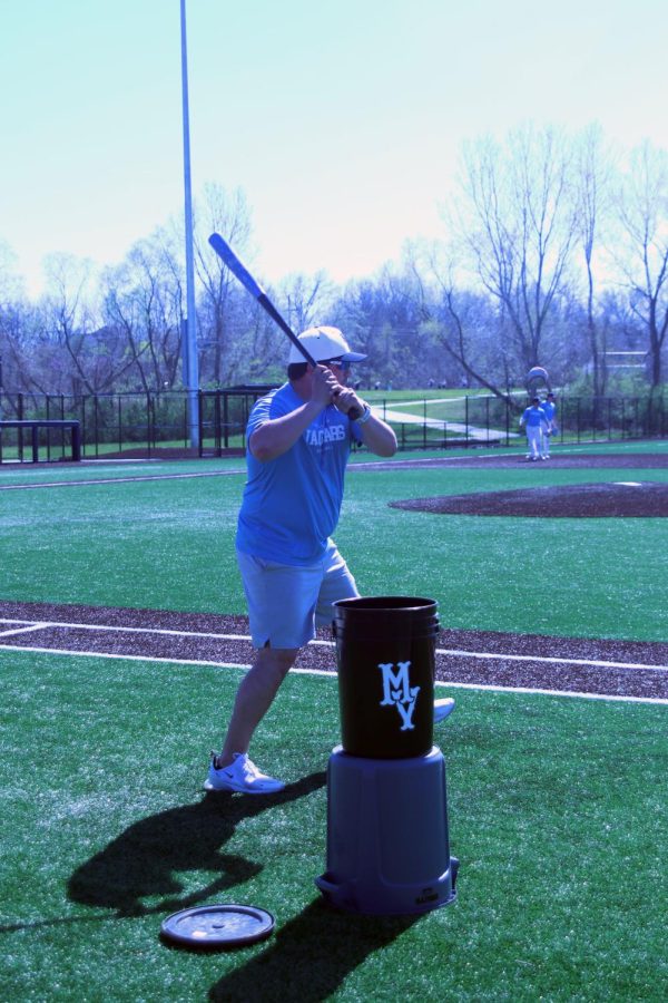 Assistant baseball coach Tim Thomas hits a ball infield to players while facilitating a catching drill Wednesday, April 12.