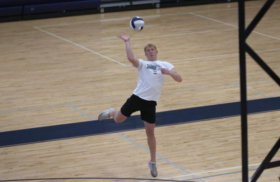 Senior Mikey Bergeron swings his arm, serving the ball over the net.