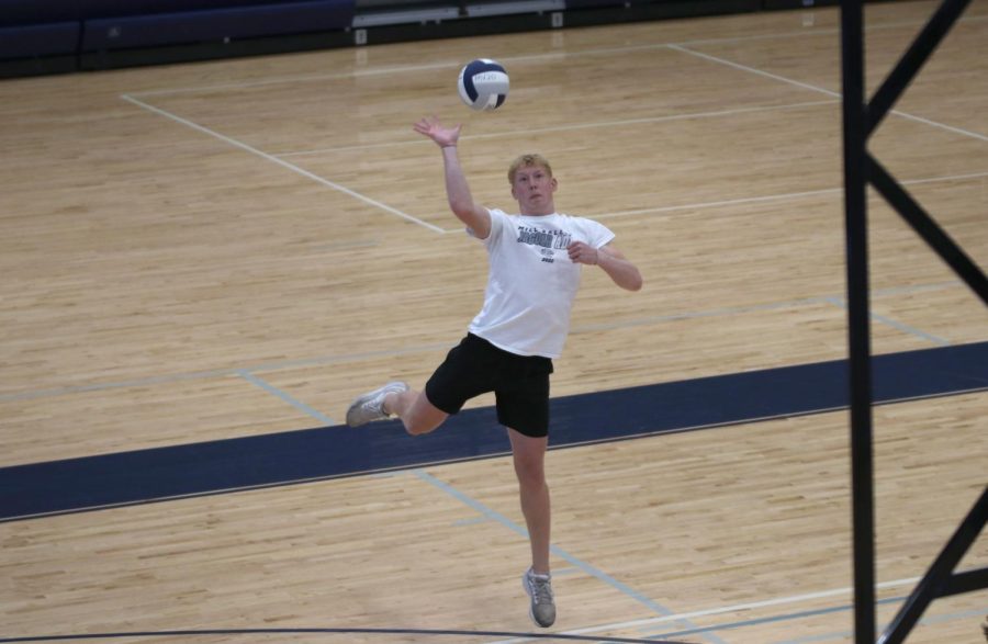 Senior Mikey Bergeron swings his arm, serving the ball over the net.