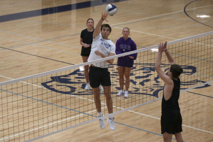 In the air, senior Marko Skavo swings his arm, hitting the ball.