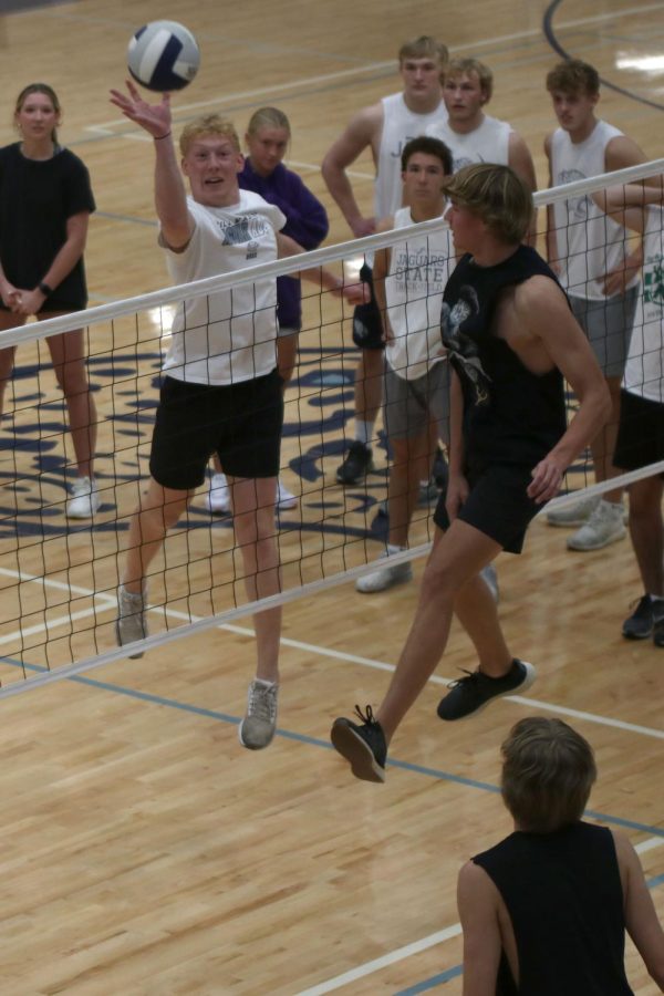 Senior Mikey Bergeron taps the ball over the net, as senior Nick Hodson attempts to block it.