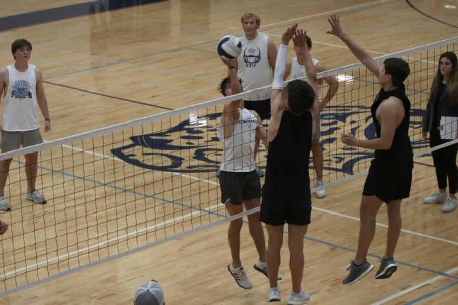  Senior Cody Geis hits the ball, as the other team attempts to black the hit.