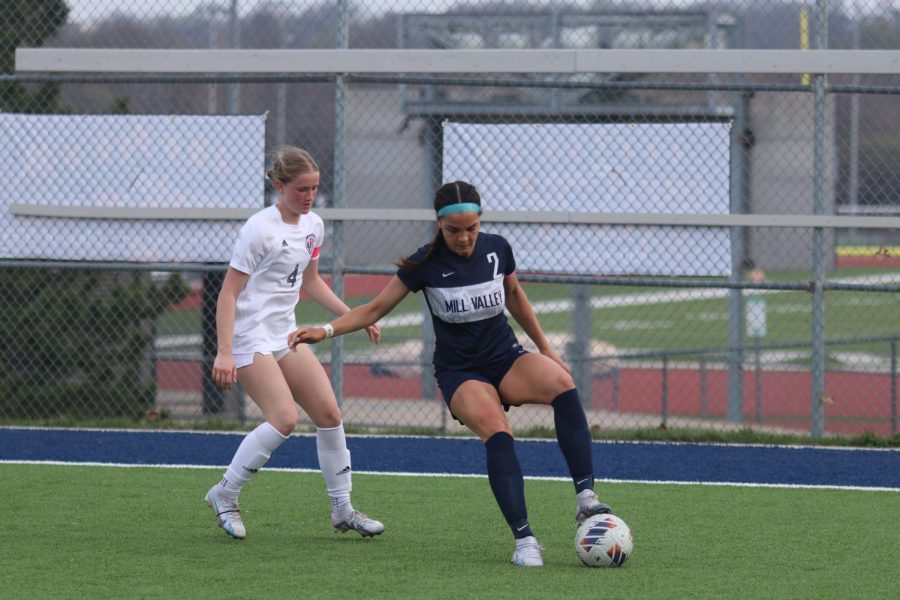 Her right arm out, senior Olivia Page blocks an Olathe North forward from the ball. 