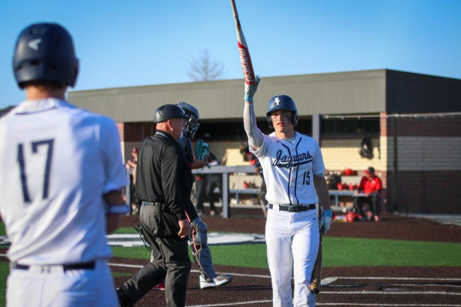 Freshman Beau Peterson tosses a new bat to junior Reid Livingston before he prepares to bat.