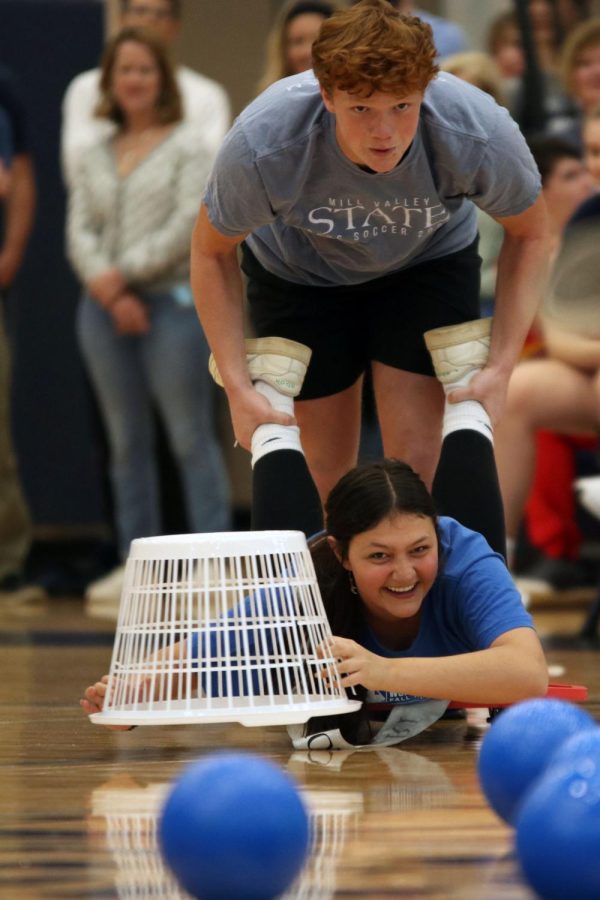 Seniors Owen Peachee pushes prom candidate partner senior Hayden Rider toward the center of the gym to try to gather more dodgeballs.