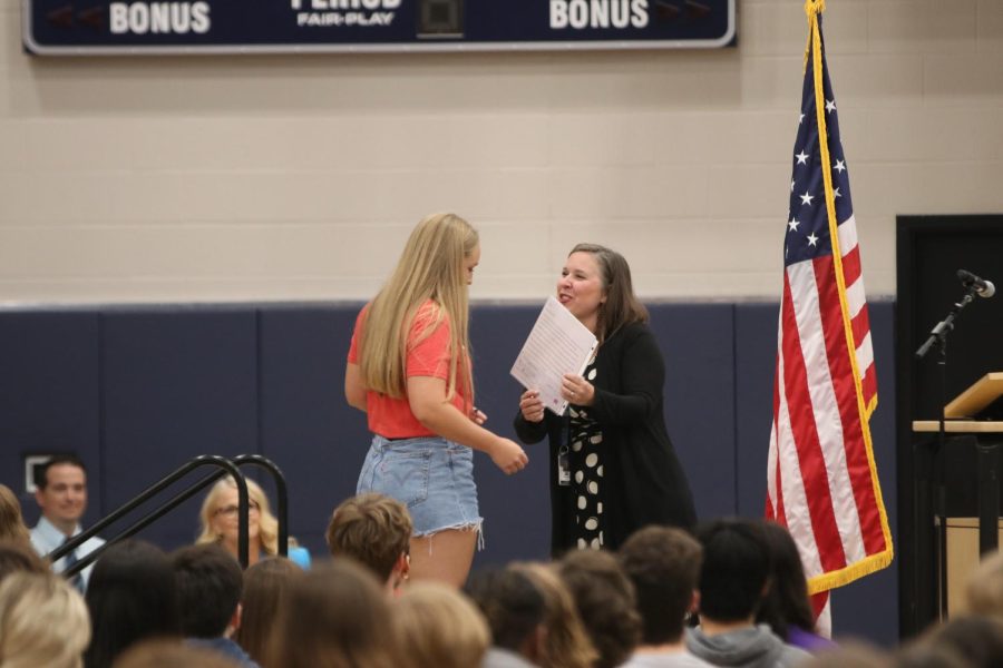 Senior Avery Blubaugh accepts the De Soto Teachers Association Scholarship from history teacher Angie DalBello.