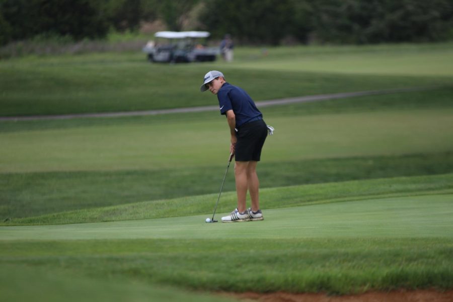 Looking towards the ball, sophomore Carter Coup lines up to putt.