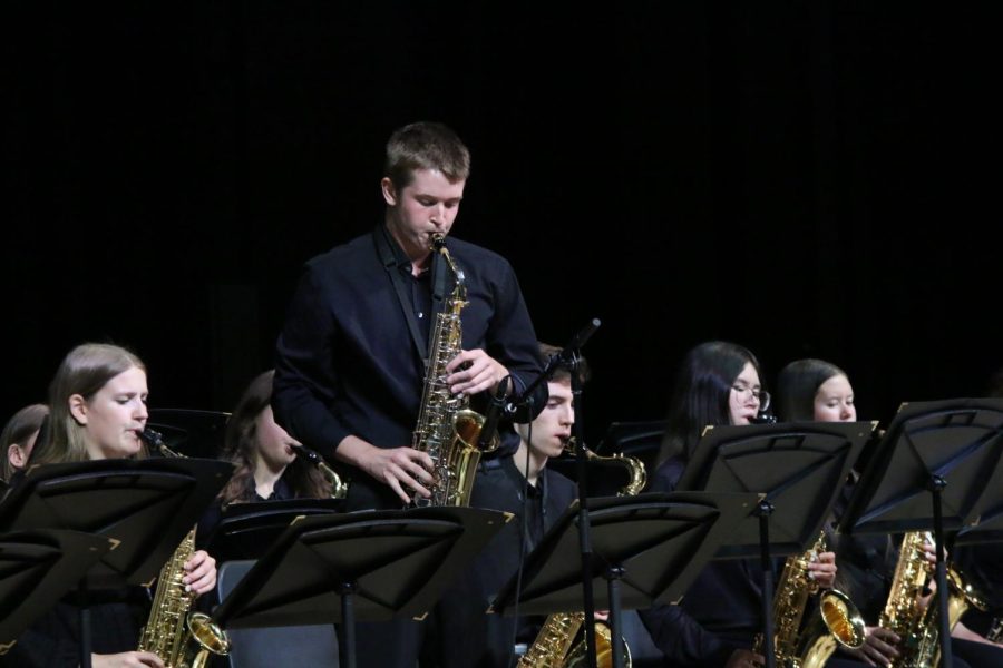 Standing up, senior Brody Shulda plays a solo on his tenor saxophone during the jazz band performance of Act Your Age. 