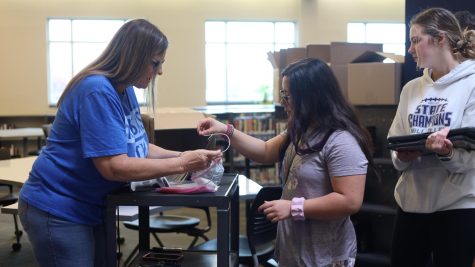 Registrar Deana Thom helps a student receive a new laptop charging cord Thursday, April 20.