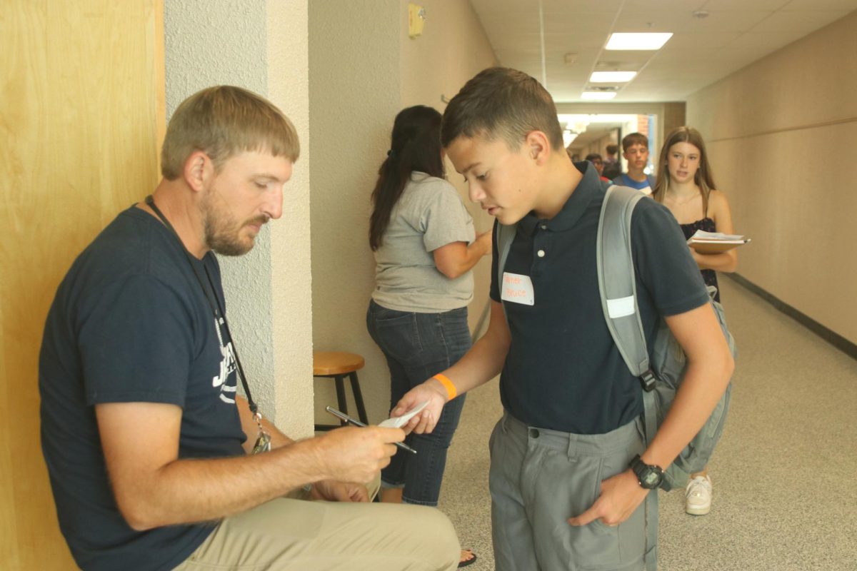 Graphic Design teacher Travis Kohler signs freshman Turner Bruce’s paper during the class scavenger hunt.