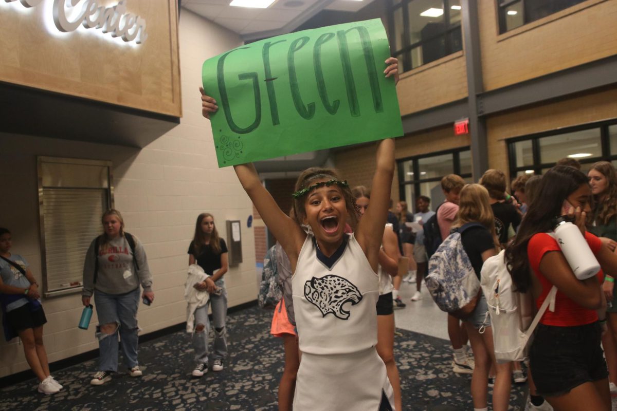 Excitedly holding up her sign, junior Jada Winfrey poses for a picture after leading the green group on the school tour.