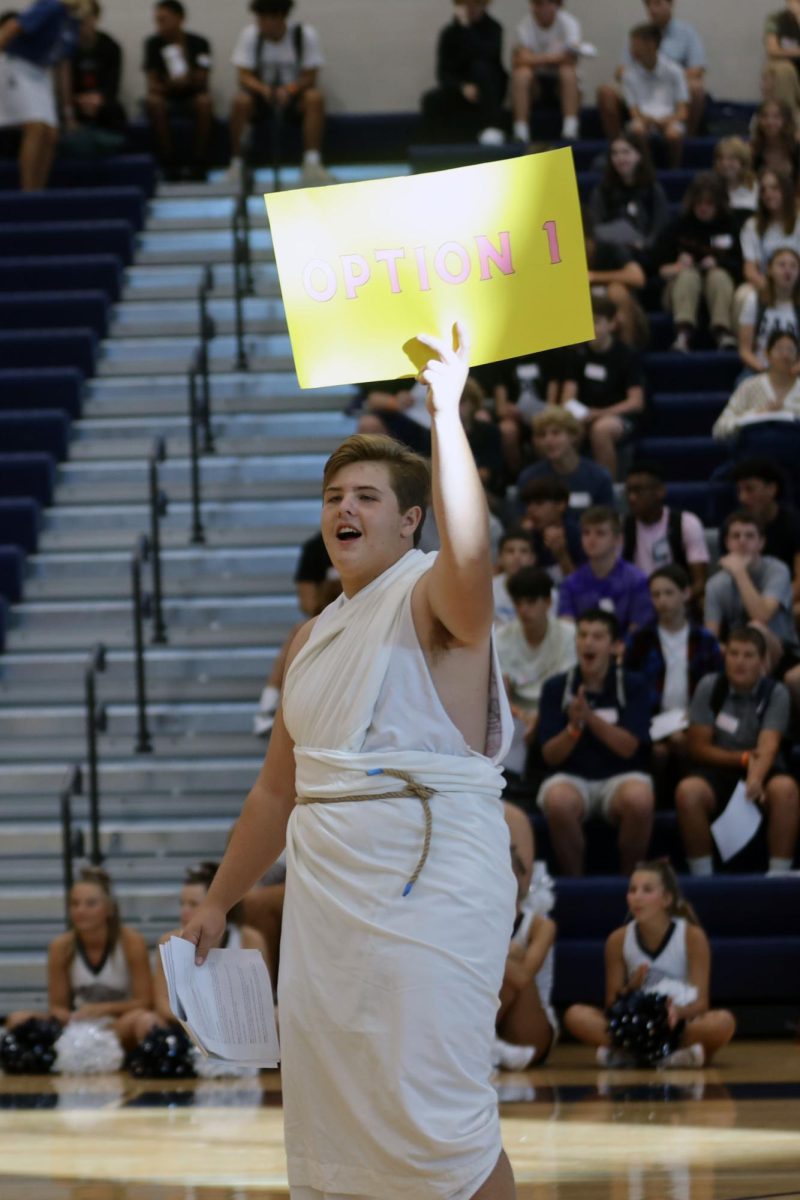 Holding up a sign, junior Hank Danielson performs his role in student councils skit for the pep assembly. 