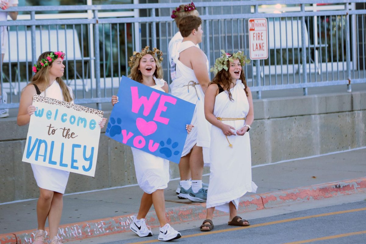 Smiling, seniors Kate Pfeister, Kynley Verdict and Ellie Walker hold signs and greet freshman. 