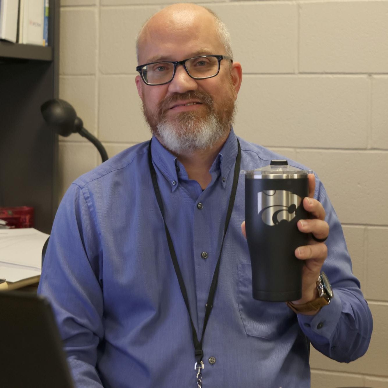 Holding his K-State mug, CAD teacher Craig Morrow sits at his desk. My wife got that for me for one of my birthdays and so that meant a lot, Morrow said.