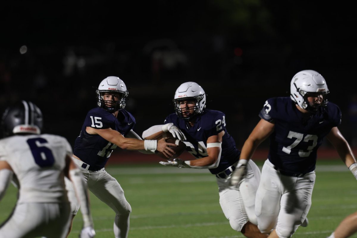 Senior Daniel Blaine hands the ball off to senior Jaden Scobee.