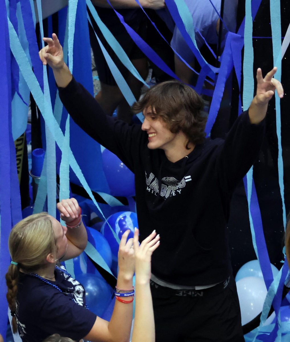 Holding up peace signs, senior Dawson Berg dances at Blue Bomb.
