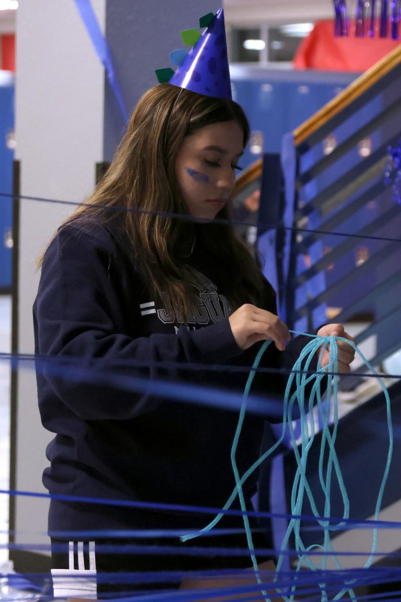 Untangling the string, senior Nathalie Gutierrez decorates under the main stairs.