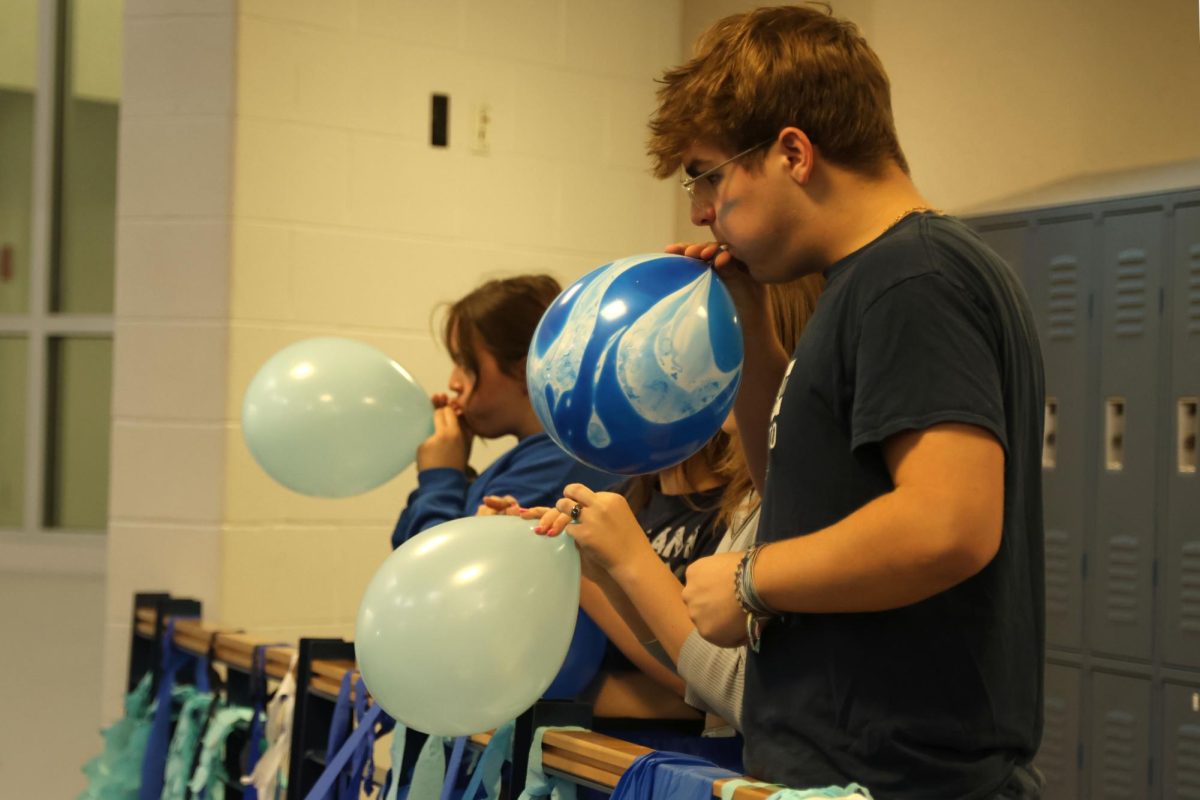 Decorating for Blue Bomb, senior Blake Powers blows up a balloon.