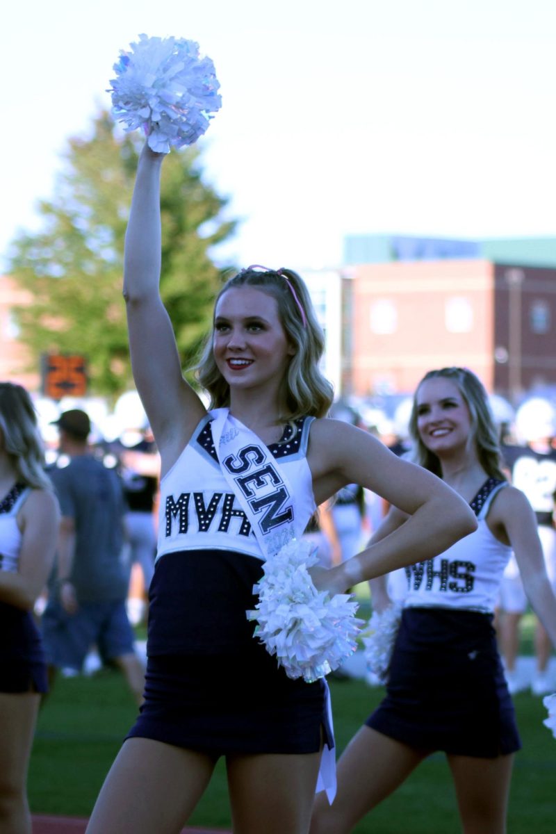 Smiling to the crowd, senior Alli Gervais holds up her pom.  