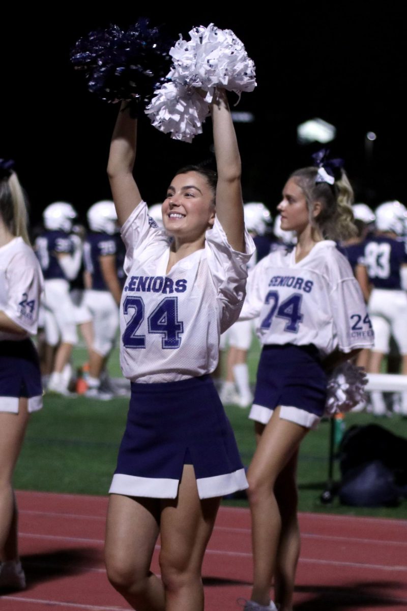 Shaking her poms in the air, senior Maddie Eppersonn performs for the student section. 