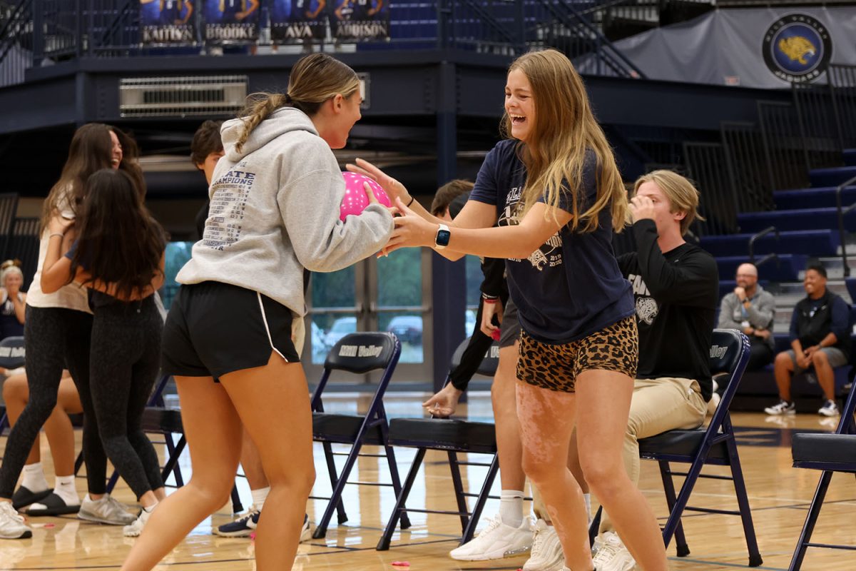 Laughing together, juniors Wren Altis and Brekhan Waters attempt to pop the balloon during the game.