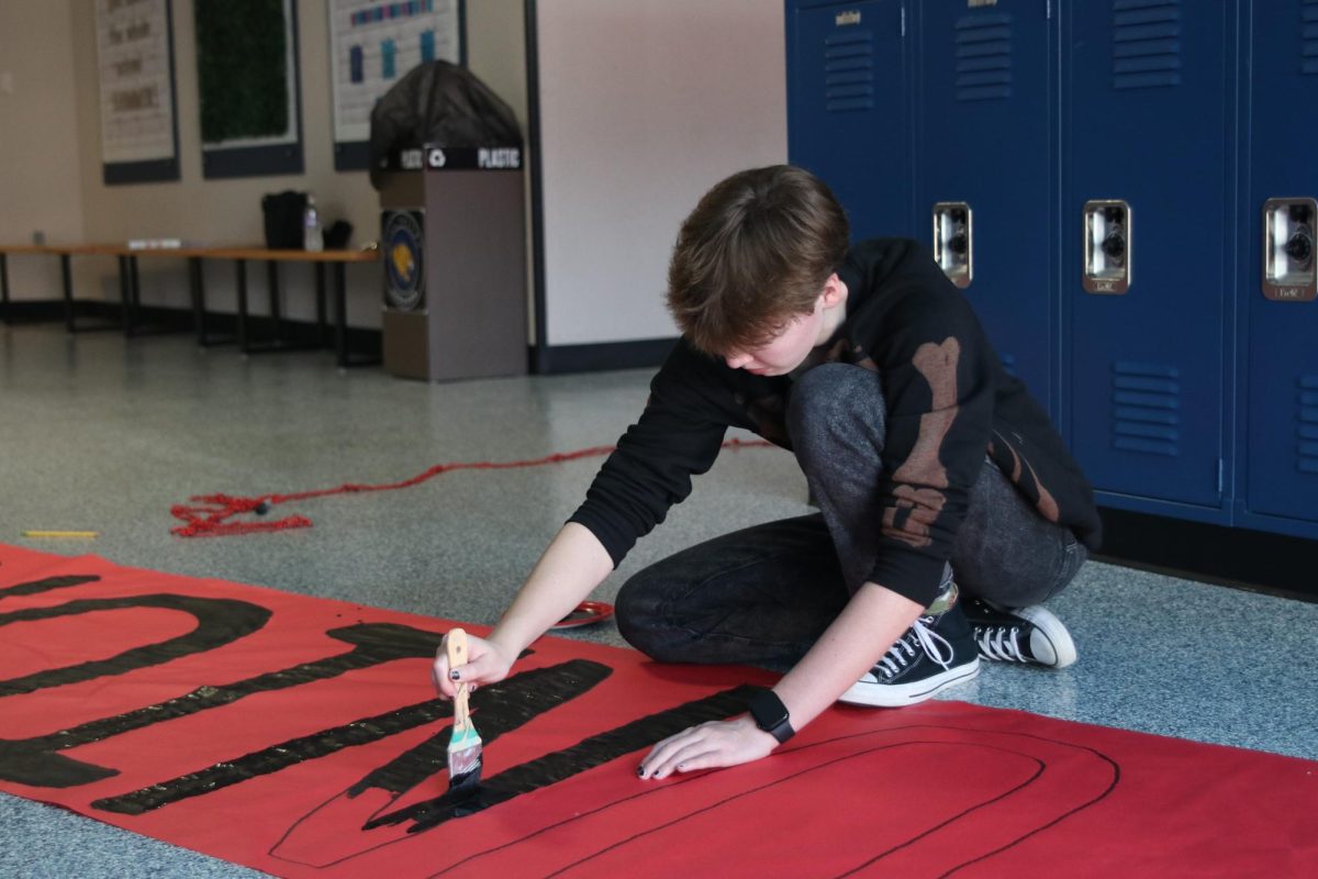 Focusing on painting, junior Cora Jones decorates for spirit week.