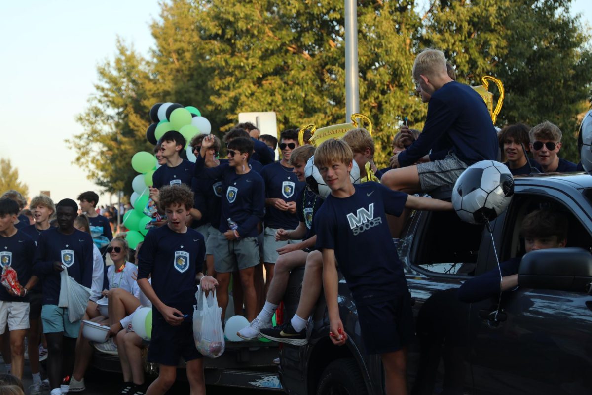 Dressed in their soccer spirit wear and spy gear, the boys soccer team rides on their float while handing out candy to the community.
