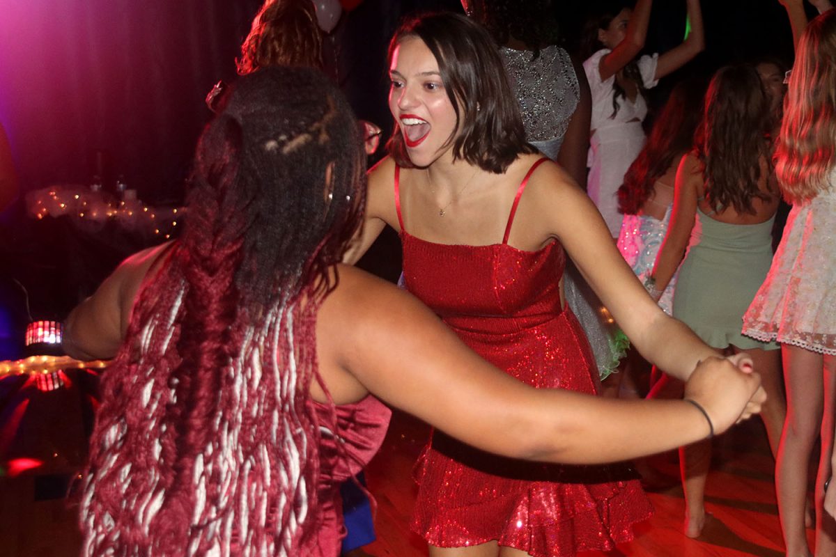 Holding hands, juniors Christina Baumgart and Autumn Graves dance and sing along to the music.