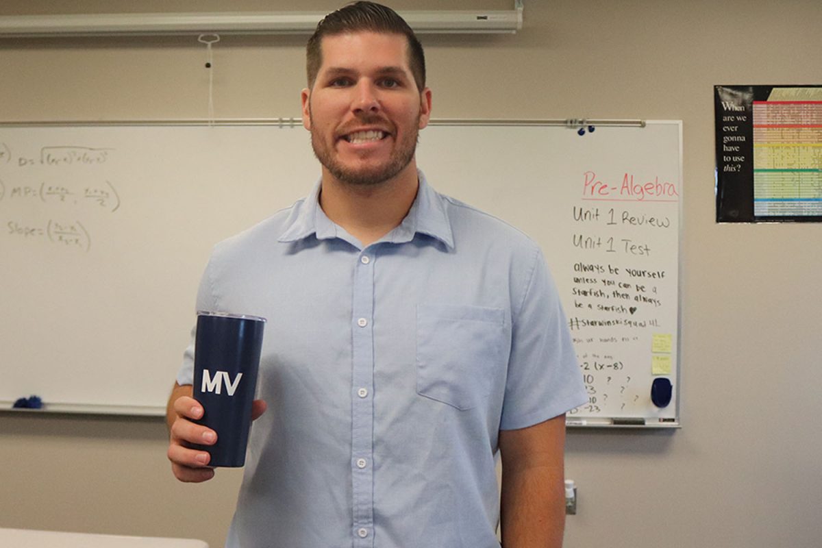 Posing in his classroom, new math teacher Patrick Sarwinski holds a Mill Valley mug.
