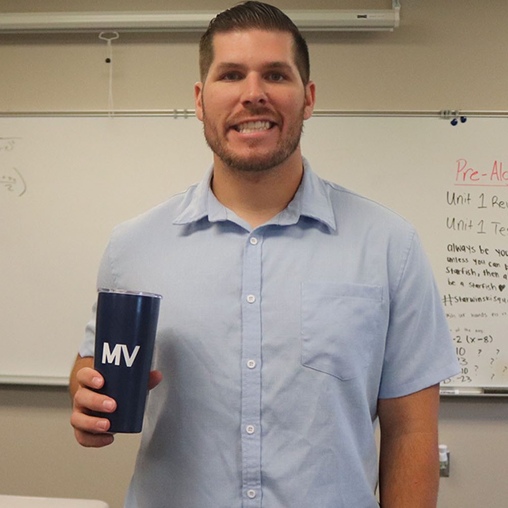 Posing in his classroom, new math teacher Patrick Sarwinski holds a Mill Valley mug.
