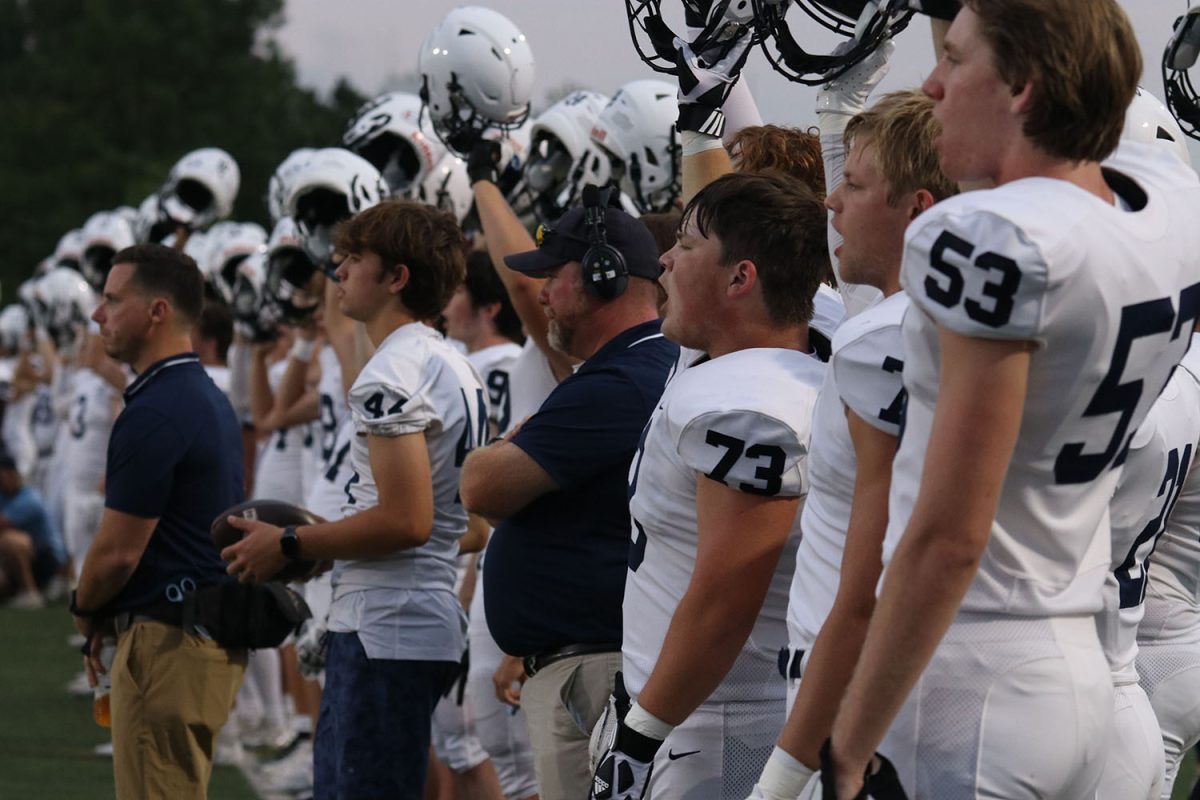 Raising his helmet in the air, junior Eric Penner yells with his teammates during the kickoff.
