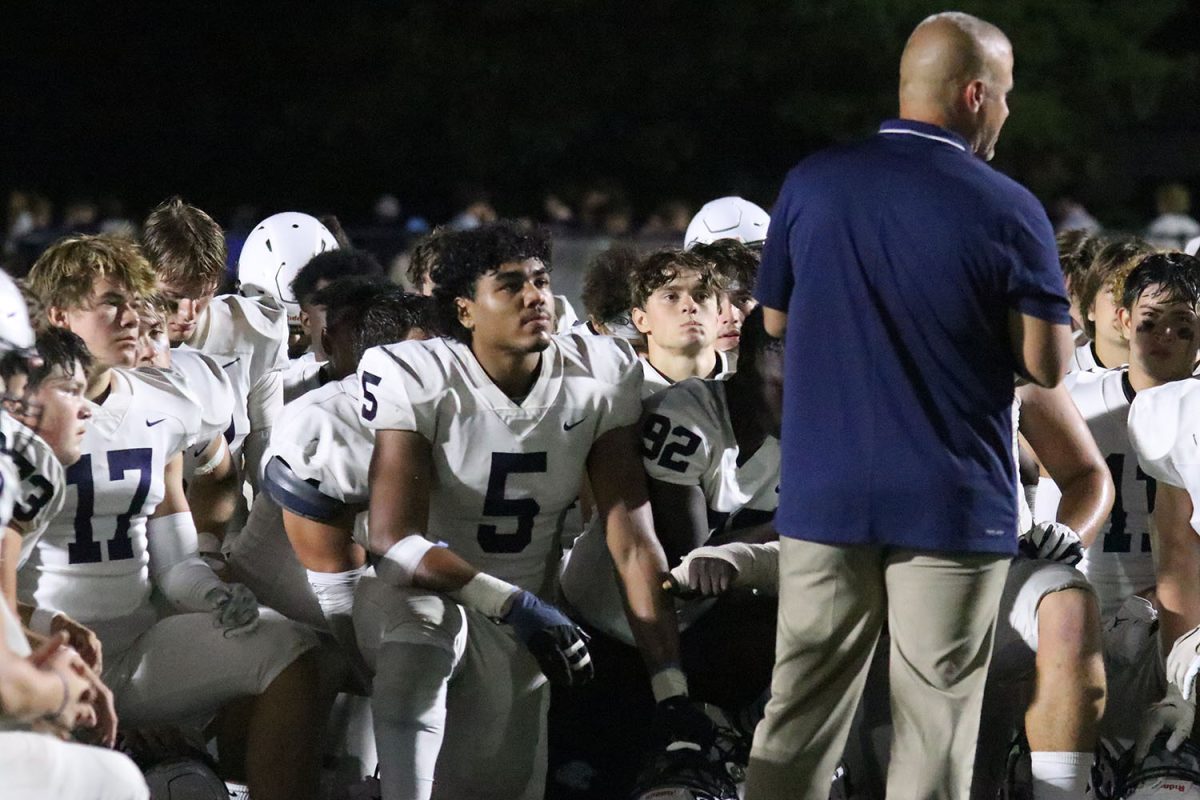 After a hard fought win, junior Jayden Woods and his teammates listen intently to head coach Joel Applebee.
